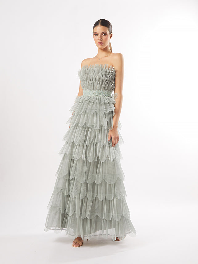 A model is showcased in a strapless tiered gown with tulle layers and embellishments, intended to be in mauve for actual garment options.
