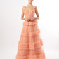 Model in a tiered peach tulle gown with textured fringes, available in peach, maroon, and pistachio, against a white backdrop.