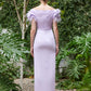 Back view of an elegant evening gown with feathered shoulders, available in lilac, dark fuchsia, and turquoise colors, showcased in a tranquil garden.