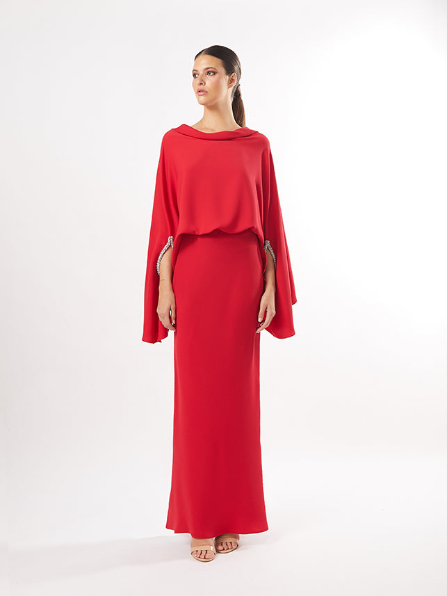 Model in a red two-piece ensemble with a flowing blouse and skirt, adorned with shoulder embellishments, also available in maroon and fuchsia.