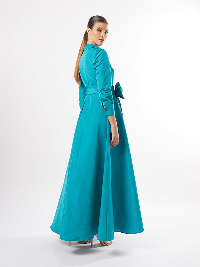 The back view of the model in the teal wrap dress, emphasizing the sleek design and tie waist, also offered in fuchsia and pistachio colors.